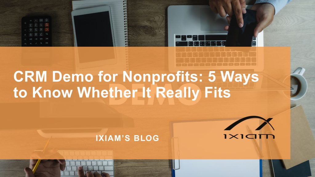 Hero image for a blog post titled 'CRM Demo for Nonprofits: 5 Ways to Know Whether It Really Fits,' with an orange translucent overlay over a workspace scene including a laptop, tablet, notebook, and coffee cup.